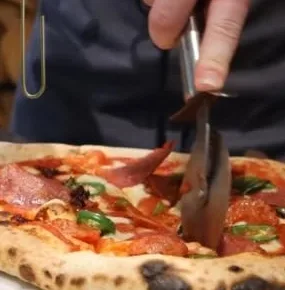 Pizza being sliced in a restaurant